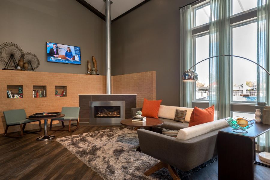 Infinity at Centerville Crossing Modern lounge with fireplace, TV, cozy seating, rug, and large windows letting in natural light.