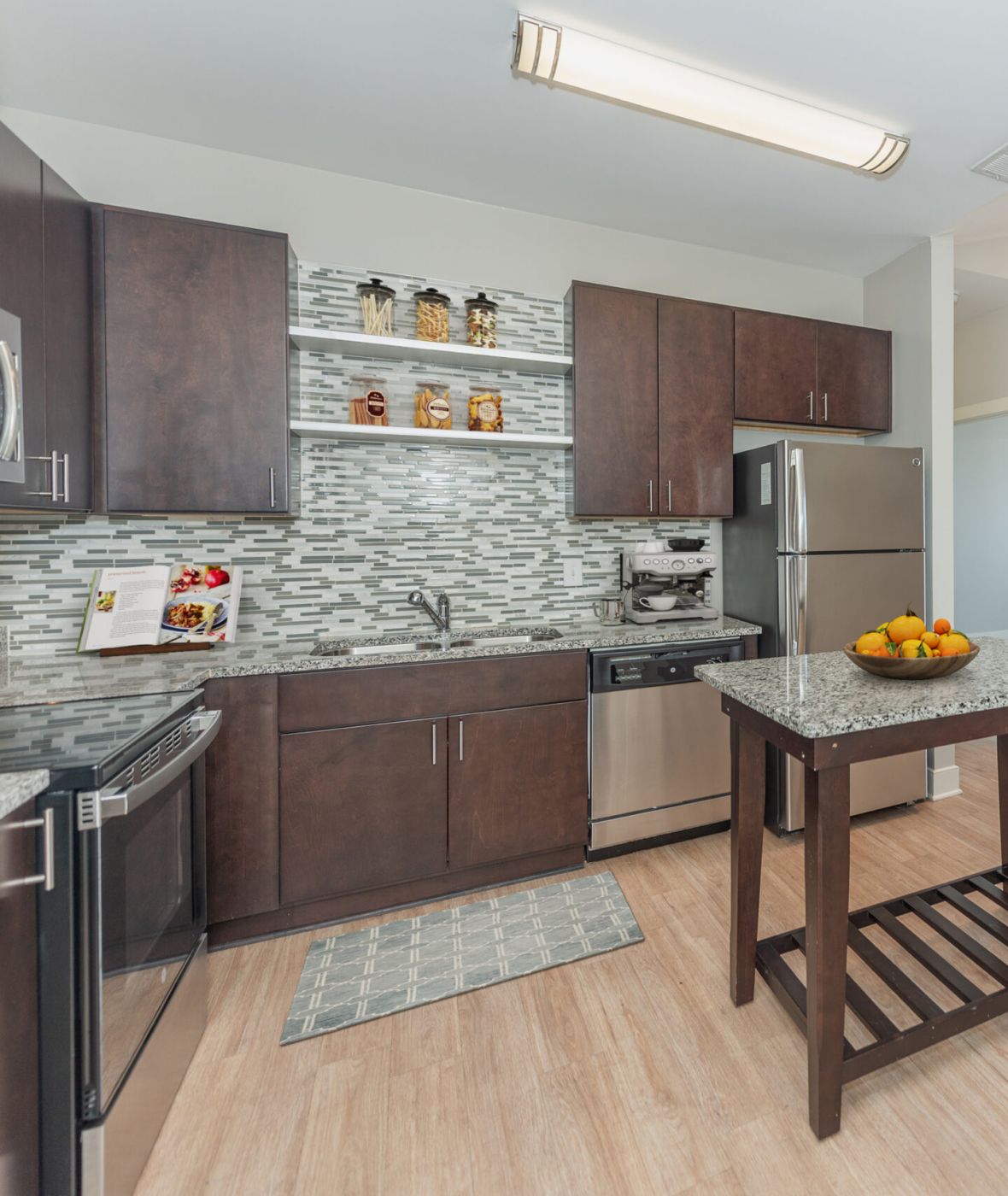 Attain on 5th apartment homes with Modern kitchen with dark cabinets, a central island, and a dining area with a round table and four chairs.