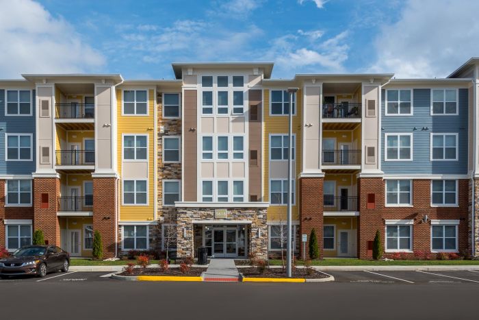 Infinity at Centerville Crossing Modern four-story apartment building with colorful facade, balconies, and a parked black car in front.