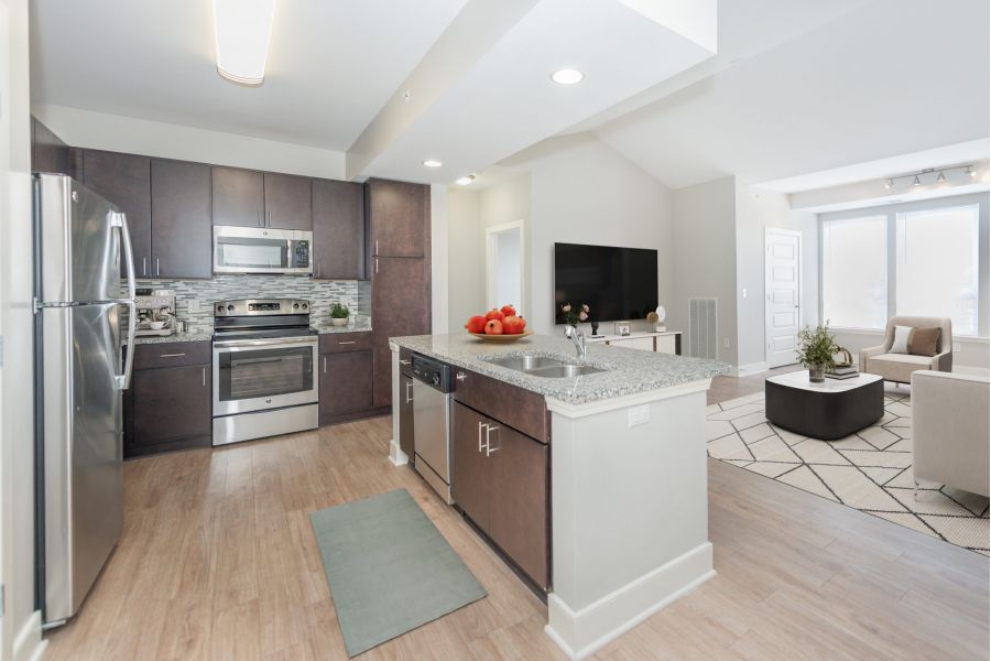 Infinity apartment homes with Modern kitchen with stainless steel appliances, island, and open view to a bright living room.