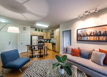 Infinity-at-Centerville-Crossing Modern open-plan living room and kitchen with stylish furniture, wall art, and contemporary decor.