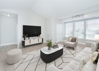 Attain on 5th apartment homes with Modern living room with neutral décor, large windows, a TV, and comfortable seating around a coffee table.