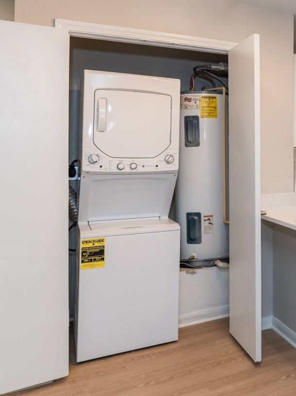 Infinity Crossings Apartments with Stacked washer and dryer unit next to two water heaters inside a closet with open doors.