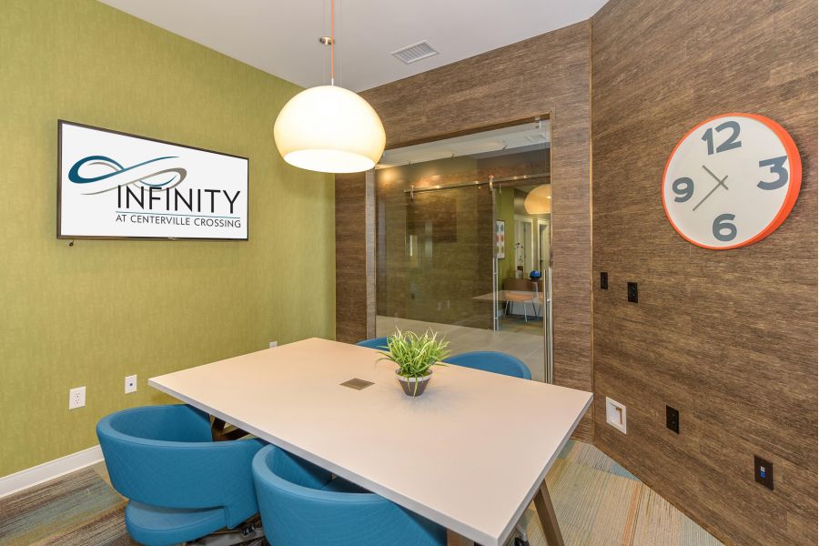 Infinity at Centerville Crossing Modern conference room with a table, blue chairs, wall clock, and "INFINITY" sign on a screen.