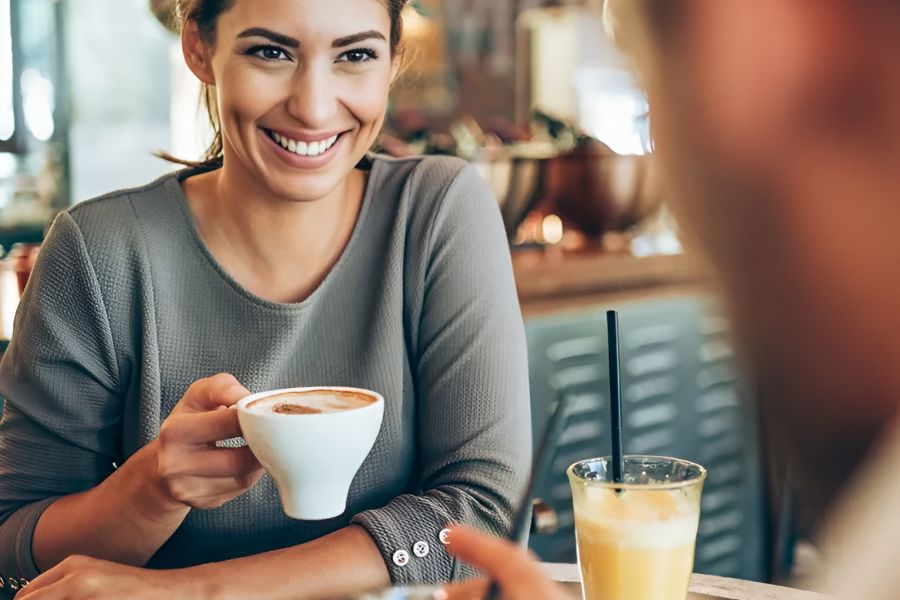 Infinity at Centerville Crossing Smiling woman holding a coffee cup, sitting at a cafe table across from another person.
