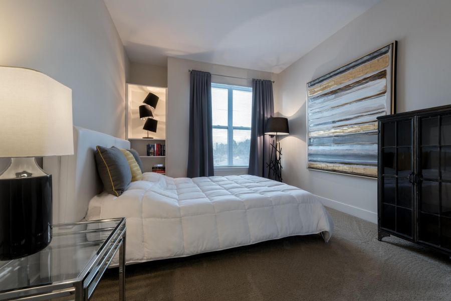 Infinity-at-Centerville-Crossing Modern bedroom with a white bed, large window, abstract wall art, and soft lighting.